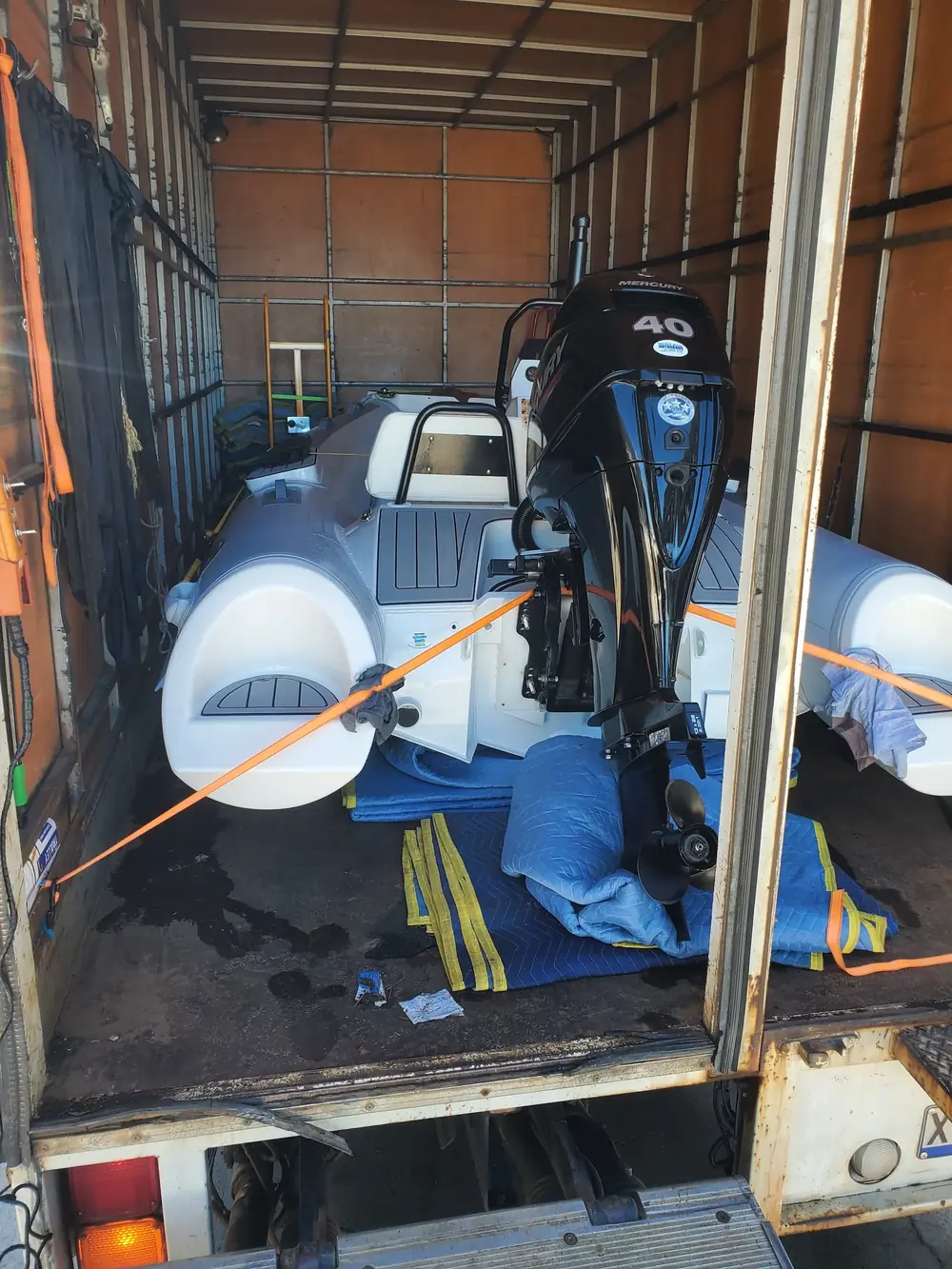 Recreational boat and outboard motor secured inside a freight truck