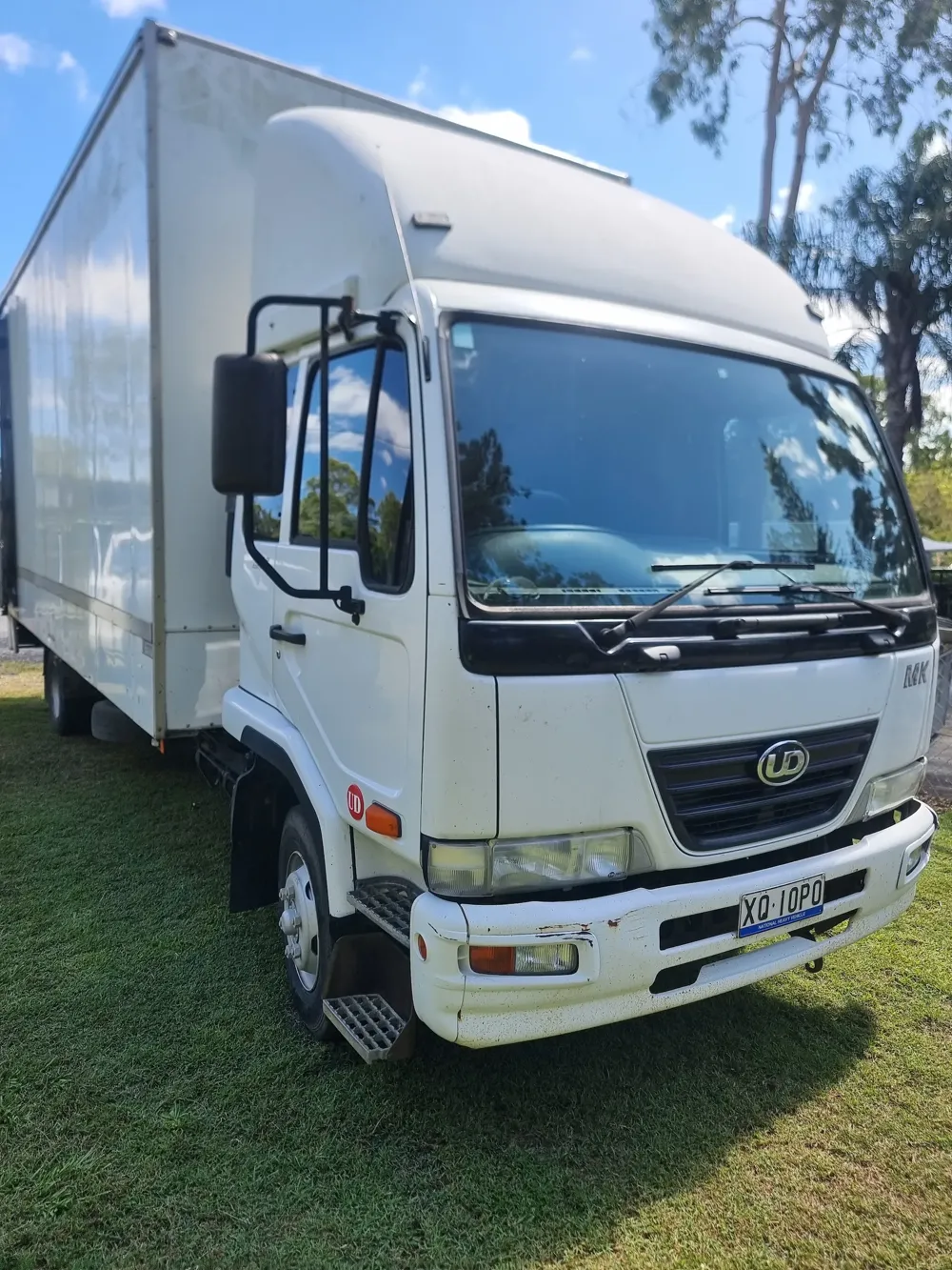 White box truck parked on grass on a sunny day