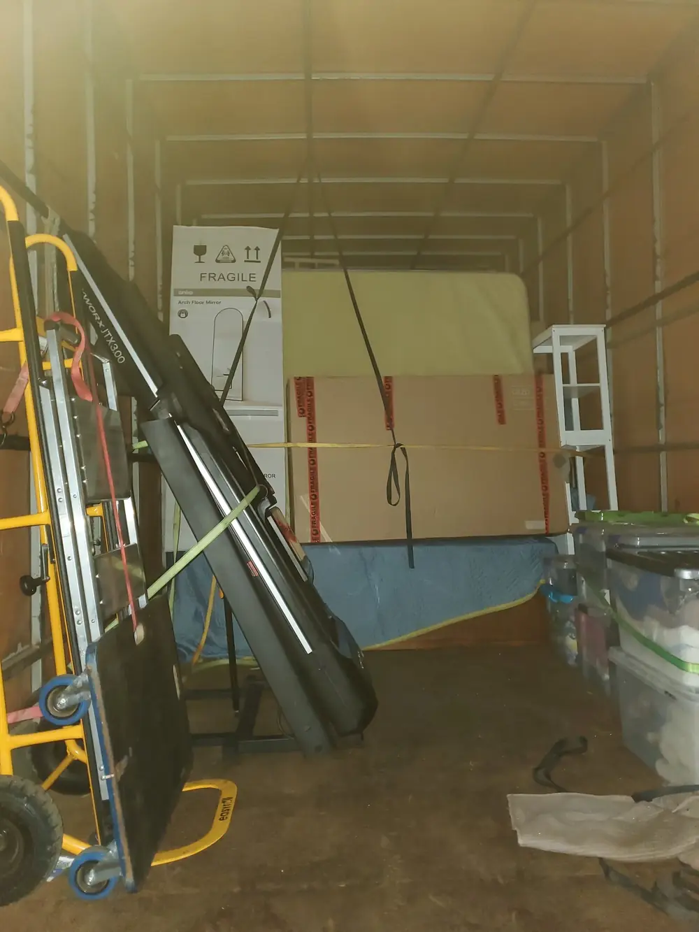 Fragile boxed item secured inside a freight truck with a dolly and loading gear